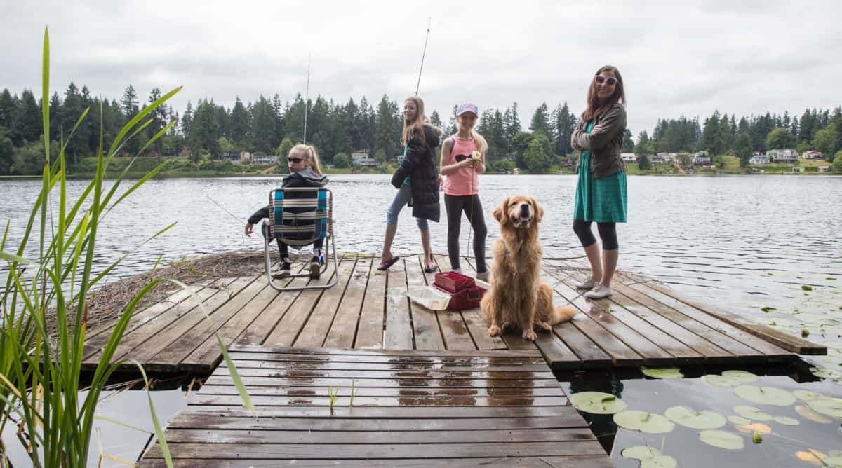 Group of girls and a dog fishing on a lake